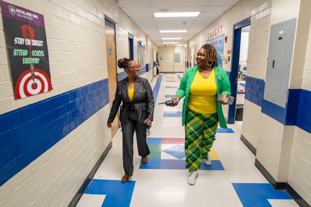 Tyra Little walking through a school with a principal