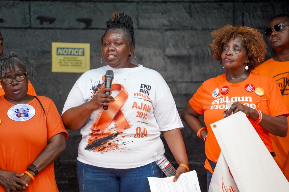 Tyra Little speaking at a Wear Orange rally surrounded by fellow advocates